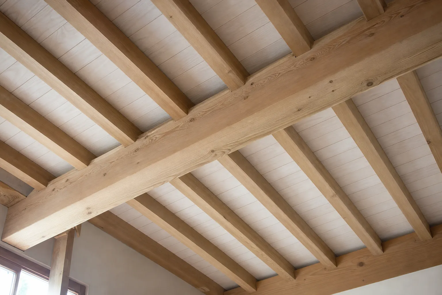 Plafond de charpente apparente terminé, chevrons et pannes en bois clair régulièrement espacés