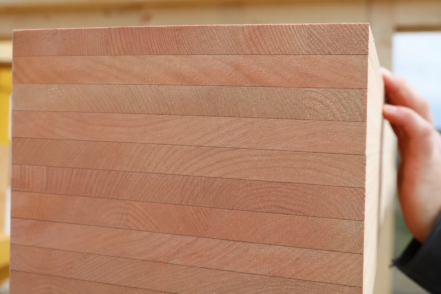 Gros plan sur une tranche de poutre en bois lamellé-collé de douglas, lamelles collées visibles