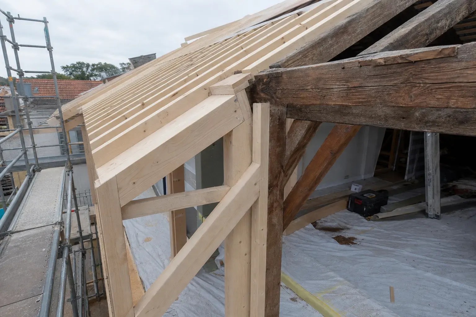 Chantier d’extension de toiture, nouvelle structure en bois clair raccordée à une charpente existante